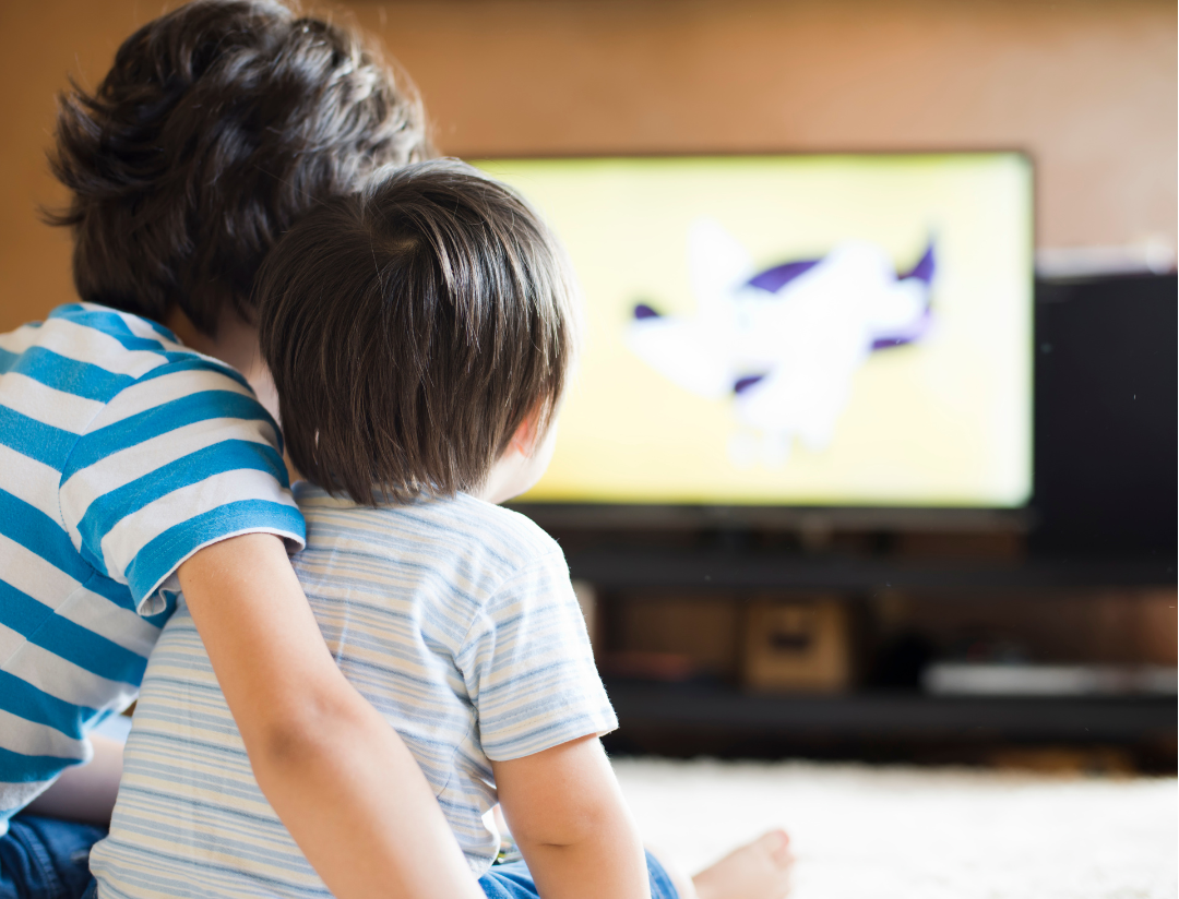 young children sitting in front of television